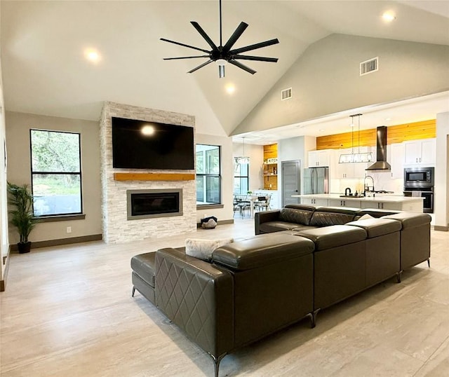 living room featuring high vaulted ceiling, baseboards, a fireplace, and visible vents