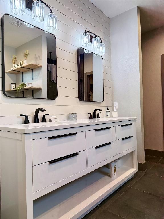 bathroom featuring tile patterned flooring, a sink, wood walls, and double vanity