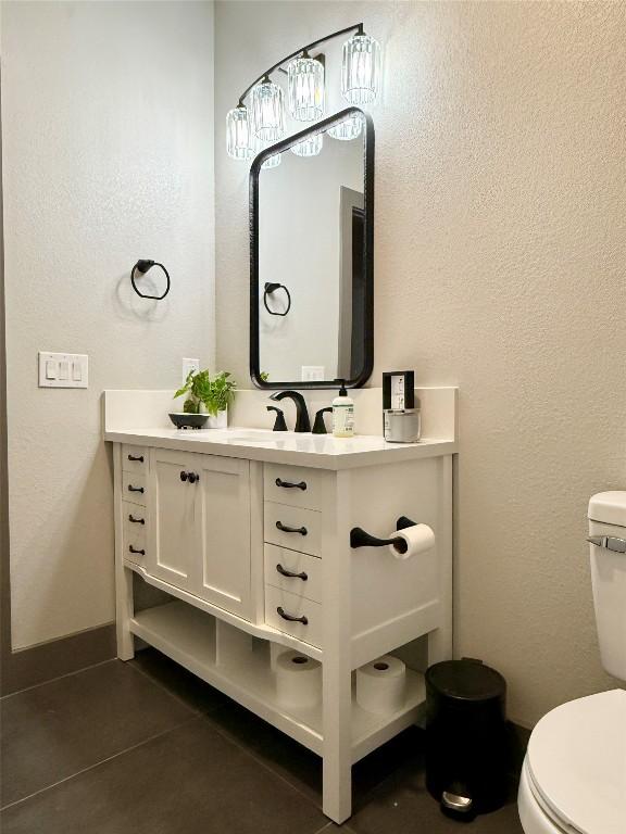 half bathroom featuring vanity, tile patterned flooring, toilet, and baseboards