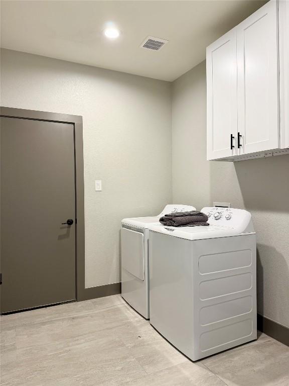 laundry room with washing machine and clothes dryer, cabinet space, visible vents, light wood-type flooring, and baseboards