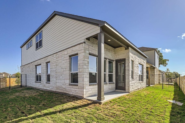 view of home's exterior with stone siding, a fenced backyard, a lawn, and a patio