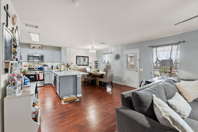 kitchen featuring dark wood finished floors, visible vents, light countertops, appliances with stainless steel finishes, and a peninsula