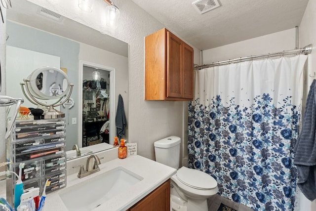 bathroom with toilet, visible vents, a textured ceiling, and vanity