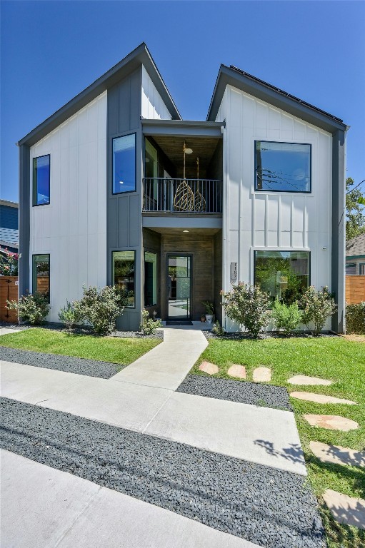 view of front of property with a balcony, board and batten siding, and a front lawn