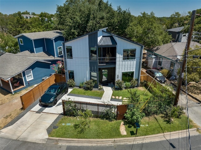 view of front of home with a standing seam roof, driveway, a fenced front yard, and metal roof