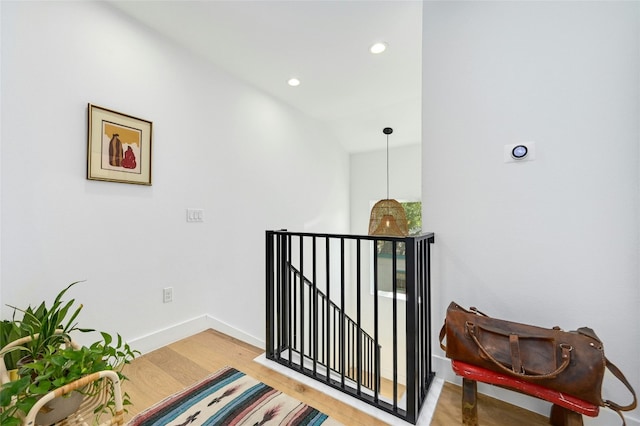 hallway with recessed lighting, baseboards, an upstairs landing, and wood finished floors