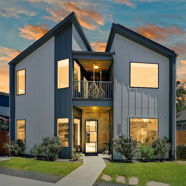 contemporary home with a balcony, board and batten siding, and a front lawn