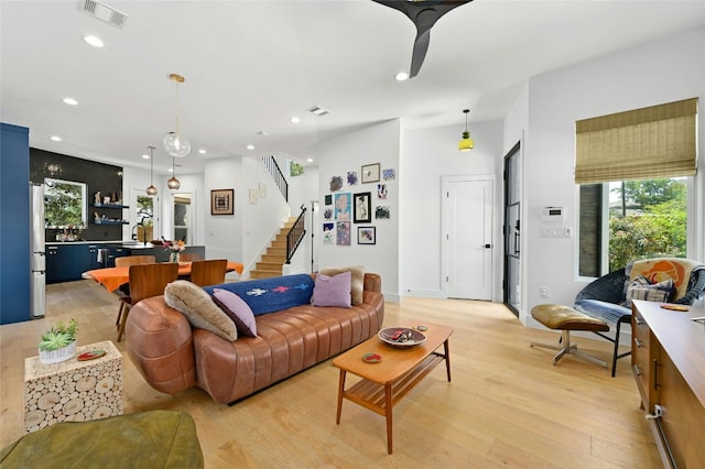 living area with light wood-type flooring, visible vents, recessed lighting, stairway, and baseboards