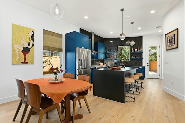 kitchen with blue cabinets, open shelves, light wood-type flooring, and stainless steel fridge with ice dispenser