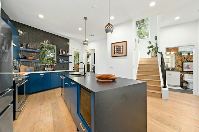 kitchen with blue cabinetry, open shelves, light wood-style floors, and a sink