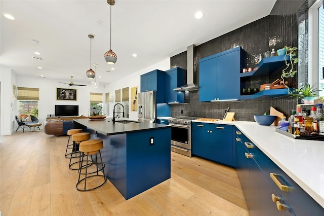 kitchen with blue cabinetry, a sink, a kitchen breakfast bar, stainless steel appliances, and light wood-style floors