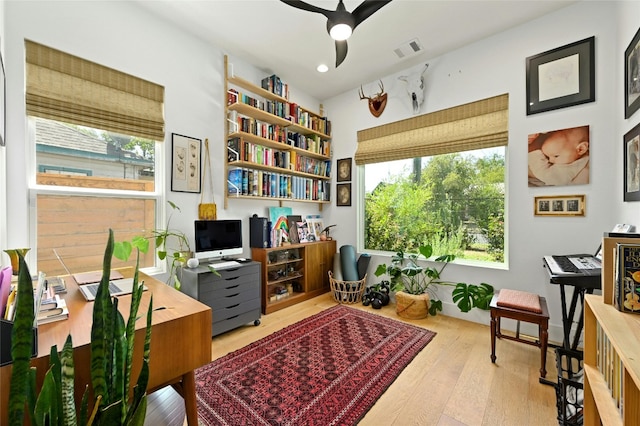 home office with visible vents, a ceiling fan, and wood-type flooring