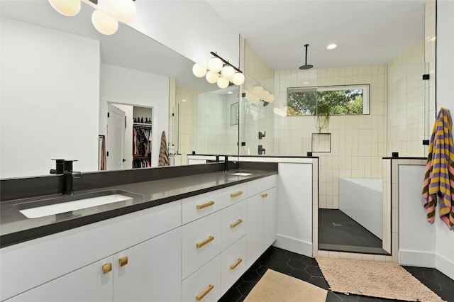 bathroom featuring double vanity, a stall shower, a sink, a walk in closet, and tile patterned floors