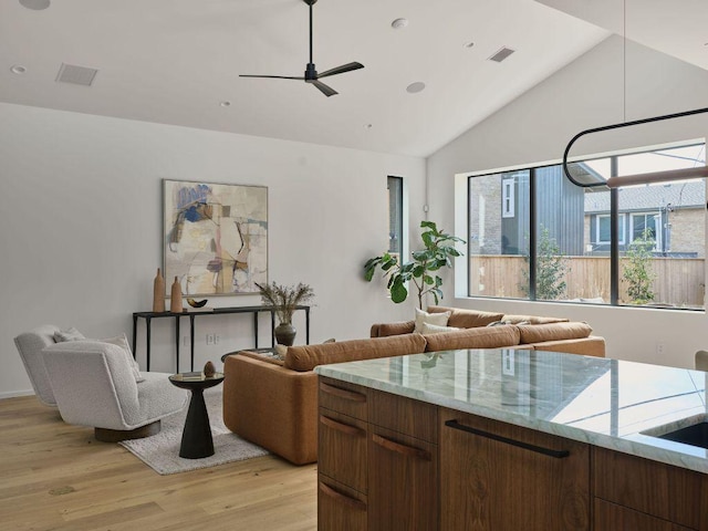 interior space featuring lofted ceiling, light wood-style flooring, visible vents, and ceiling fan