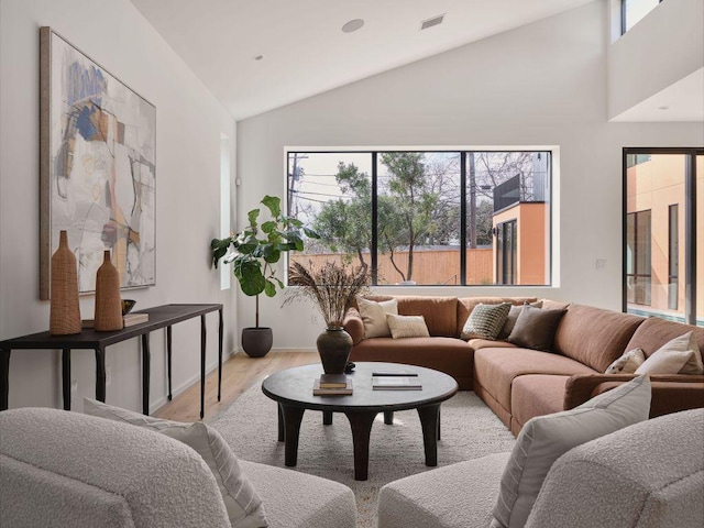 living room featuring high vaulted ceiling, visible vents, and wood finished floors