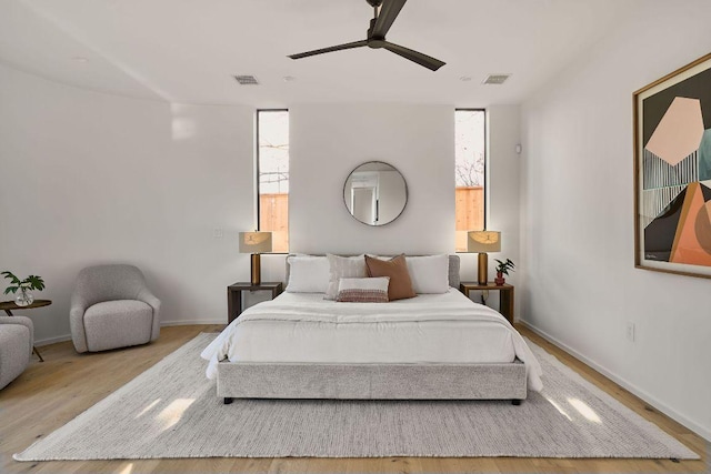 bedroom featuring baseboards, ceiling fan, visible vents, and wood finished floors