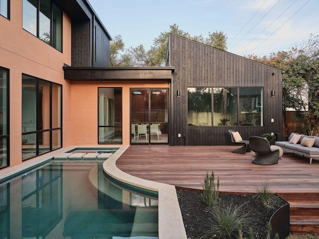 rear view of property with a deck, an in ground hot tub, and an outdoor living space