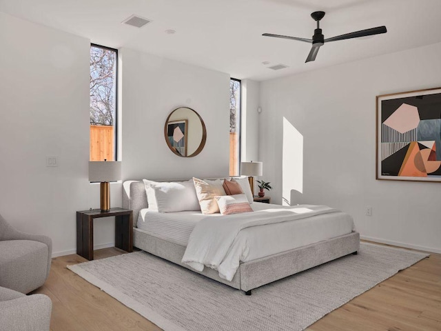 bedroom featuring a ceiling fan, visible vents, baseboards, and wood finished floors