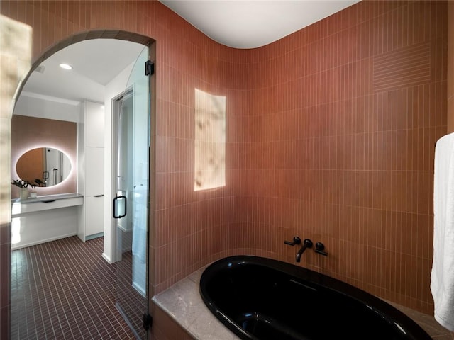 full bath with a tub to relax in, tile walls, and tile patterned floors