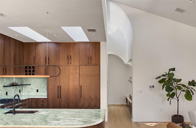 kitchen with light wood-type flooring, modern cabinets, visible vents, and a sink