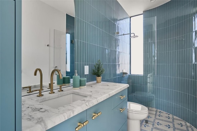 bathroom with a tile shower, tile walls, toilet, and vanity