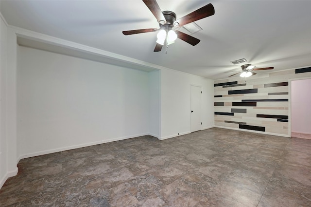 interior space with an accent wall, a ceiling fan, visible vents, and baseboards