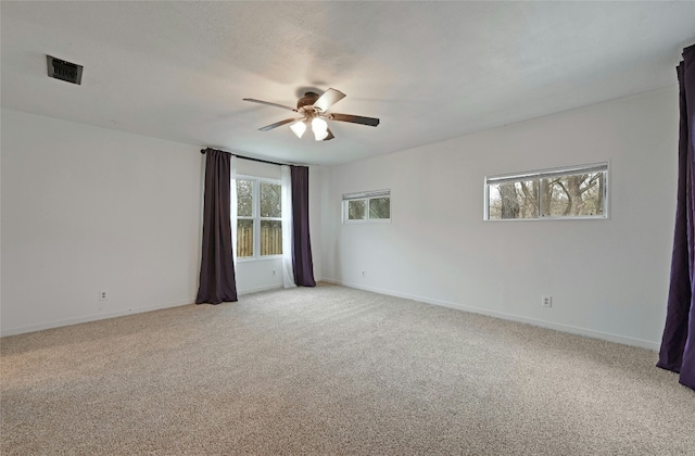 spare room with a ceiling fan, visible vents, light carpet, and baseboards