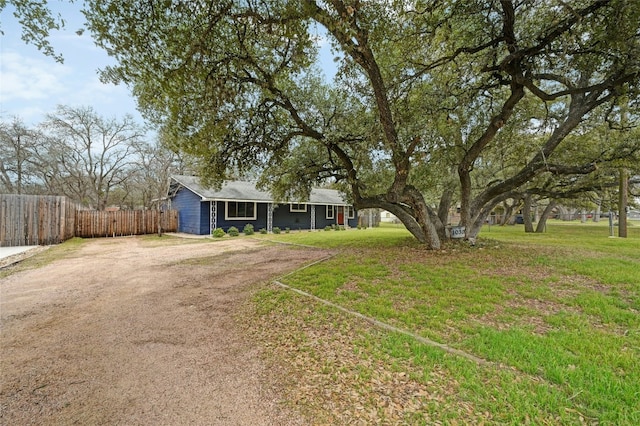 ranch-style house with driveway, fence, and a front lawn