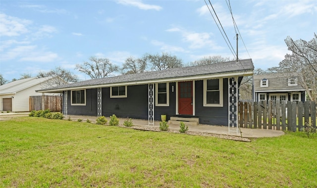 ranch-style home featuring covered porch, a shingled roof, fence, and a front lawn