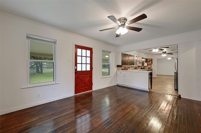 interior space featuring ornamental molding, dark wood-style flooring, ceiling fan, and baseboards