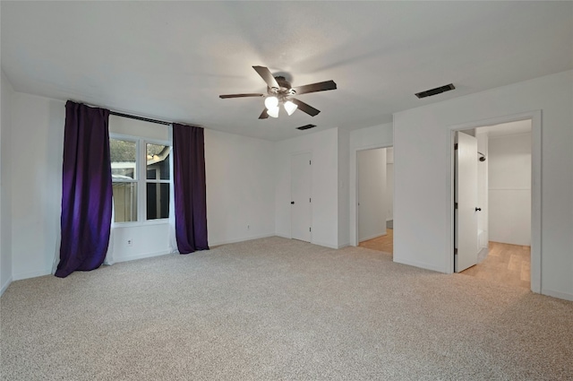 spare room with light carpet, ceiling fan, and visible vents