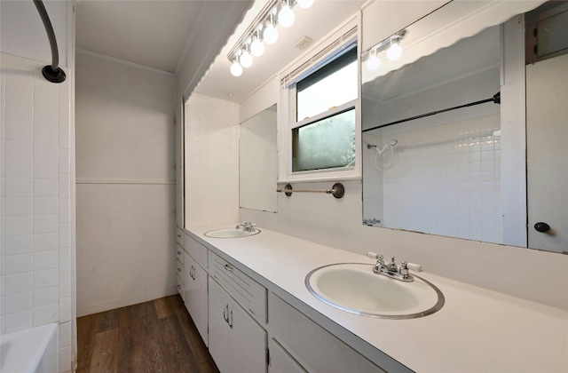 bathroom featuring a wainscoted wall, double vanity, wood finished floors, and a sink