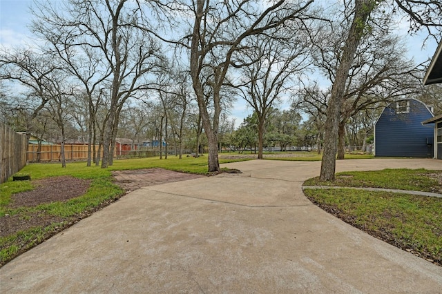 surrounding community with concrete driveway, a lawn, and fence