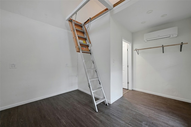 interior space featuring a wall unit AC, baseboards, and wood finished floors