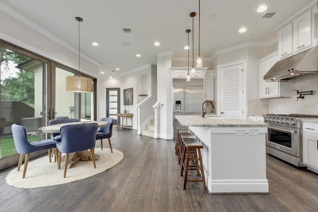 kitchen with premium appliances, visible vents, dark wood finished floors, and under cabinet range hood