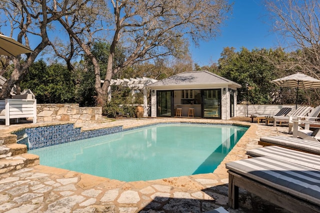 outdoor pool with a storage structure, a patio area, fence, and an outbuilding