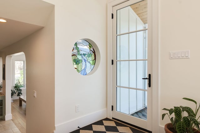 doorway to outside featuring arched walkways and baseboards