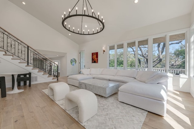 living room with high vaulted ceiling, wood finished floors, plenty of natural light, and stairs