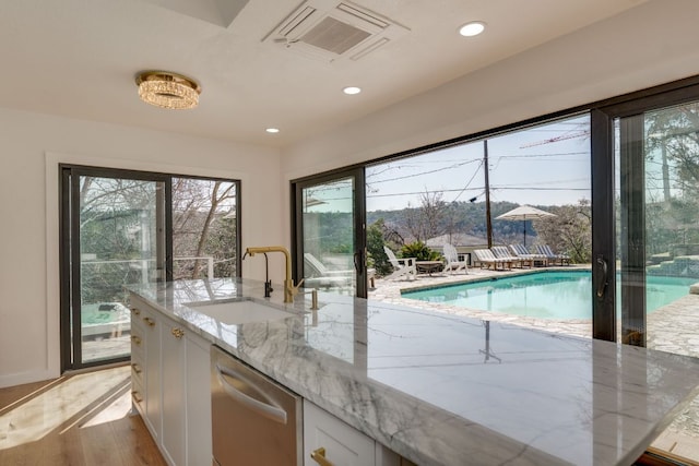 interior space featuring light stone counters, visible vents, white cabinets, a sink, and plenty of natural light