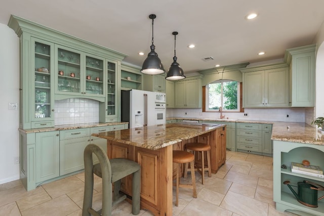 kitchen featuring white appliances, visible vents, green cabinets, a center island, and open shelves