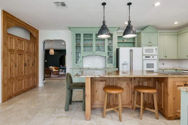 kitchen with arched walkways, white appliances, visible vents, green cabinets, and decorative backsplash