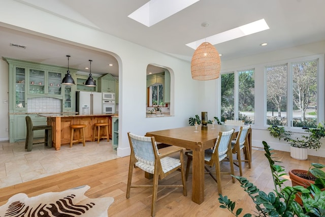 dining space featuring recessed lighting, visible vents, light wood-style flooring, and a skylight