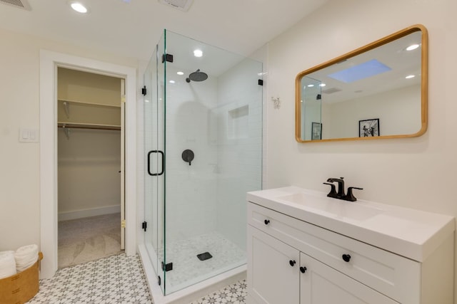 full bath featuring a stall shower, a walk in closet, vanity, and recessed lighting