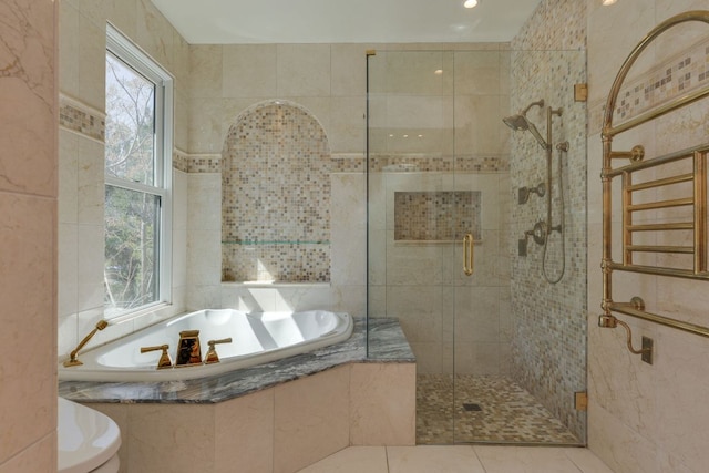 bathroom with tile patterned flooring, a shower stall, a bath, and tile walls