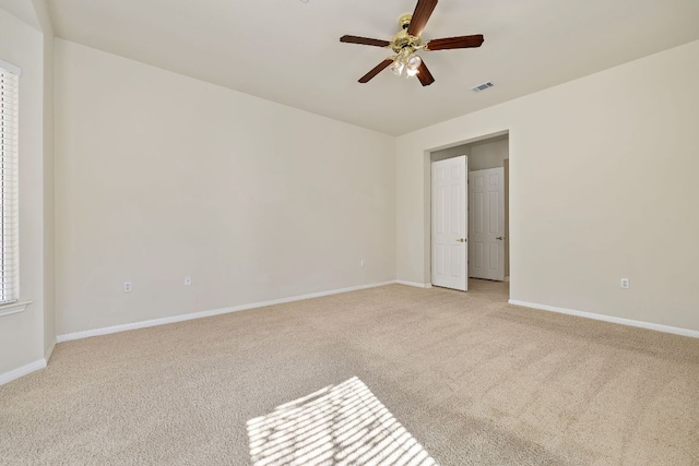 unfurnished room with visible vents, baseboards, a ceiling fan, and light colored carpet