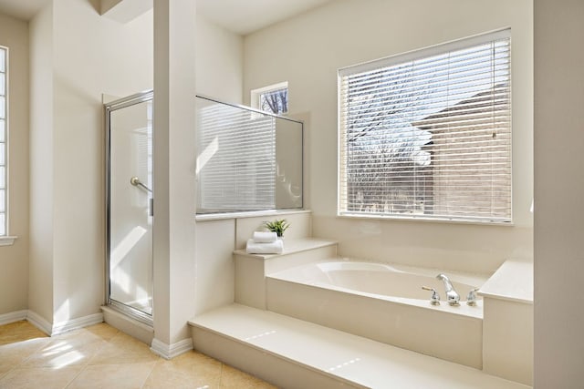 bathroom with a garden tub, a shower stall, baseboards, and tile patterned flooring