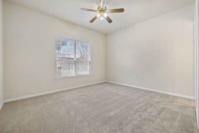 carpeted empty room featuring a ceiling fan and baseboards