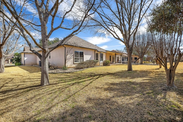 exterior space with a garage, stucco siding, and a yard