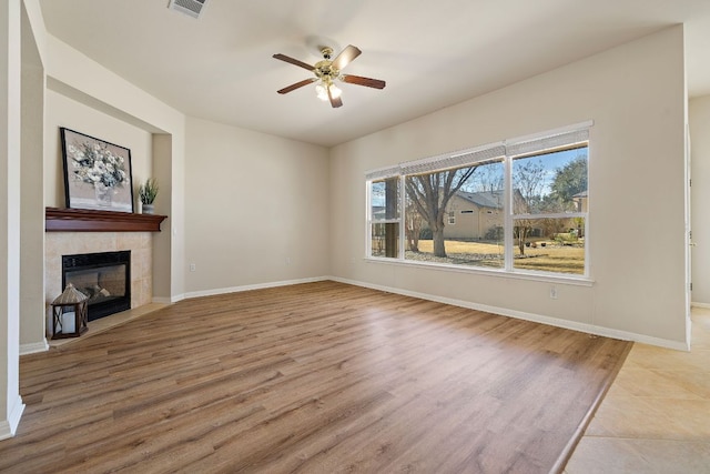 unfurnished living room with a fireplace, baseboards, and wood finished floors