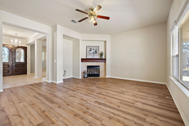 unfurnished living room with baseboards, visible vents, a tiled fireplace, and wood finished floors